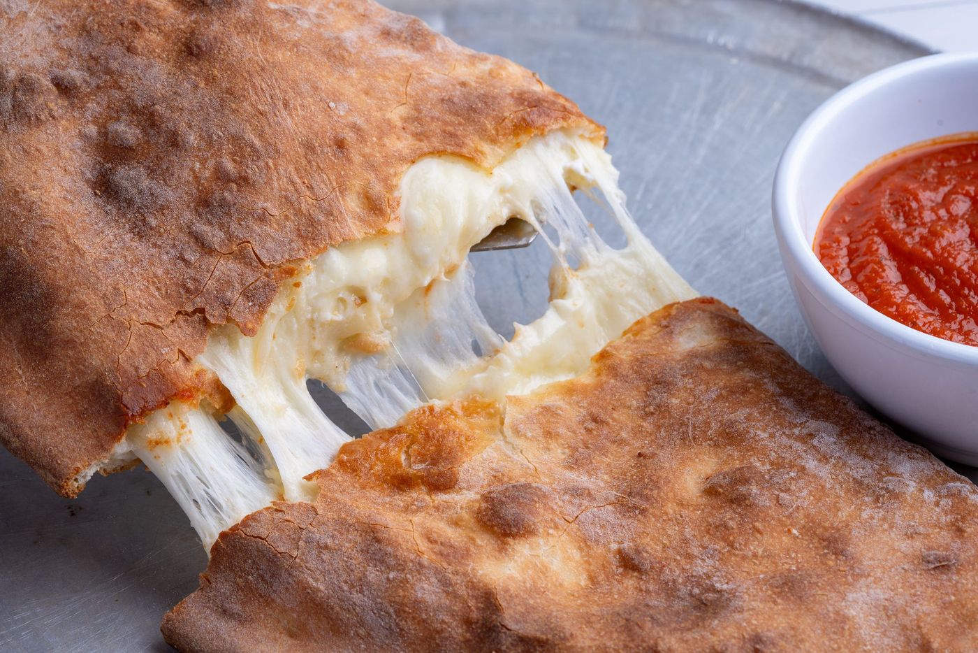 A calzone pulled open with melted cheese and marinara