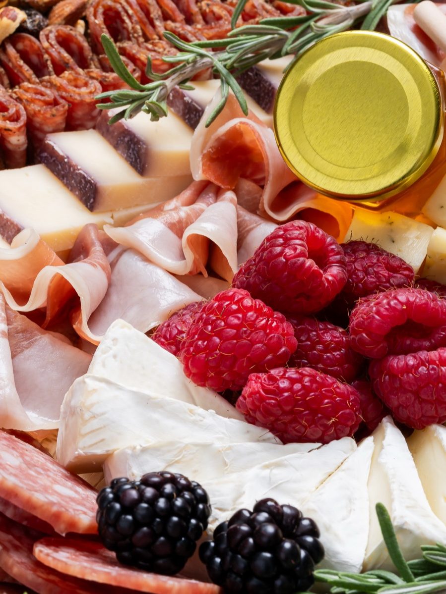 A charcuterie board with cheeses, cured meats and raspberries