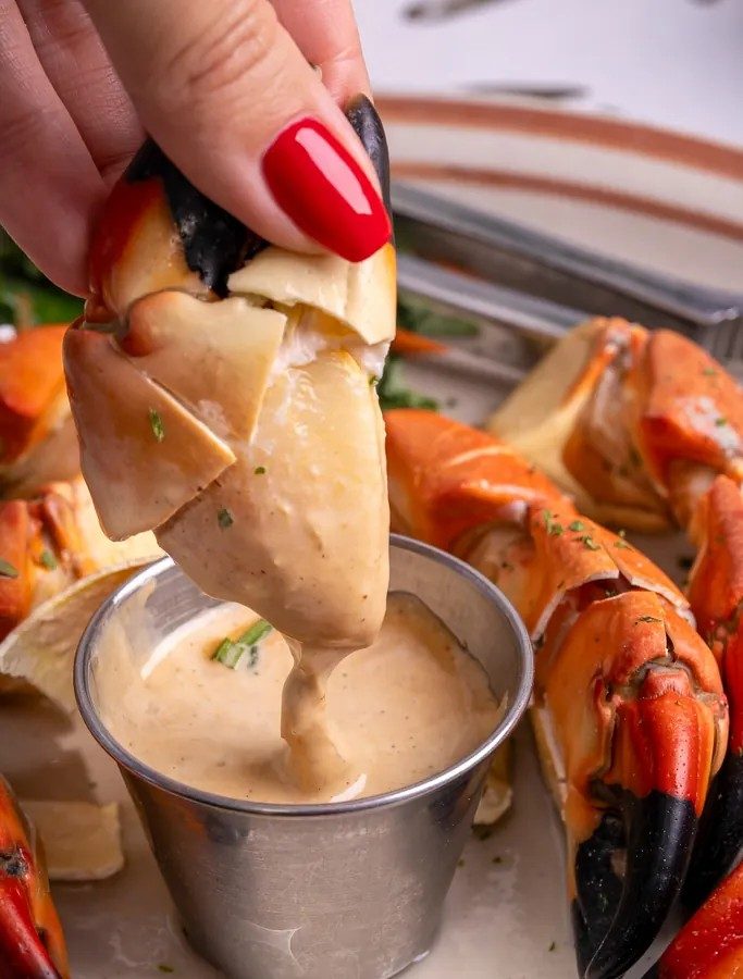 A stone crab claw dipped in mustard sauce
